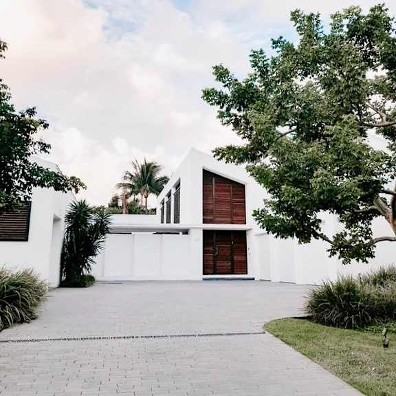 a white house with a red door and a tree in front.