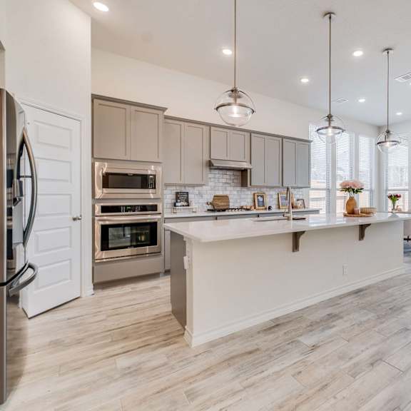 a modern kitchen with a refrigerator on the left and a dining area with a white couch.