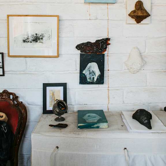 a white brick wall with a variety of objects including a globe, books, and framed pictures.