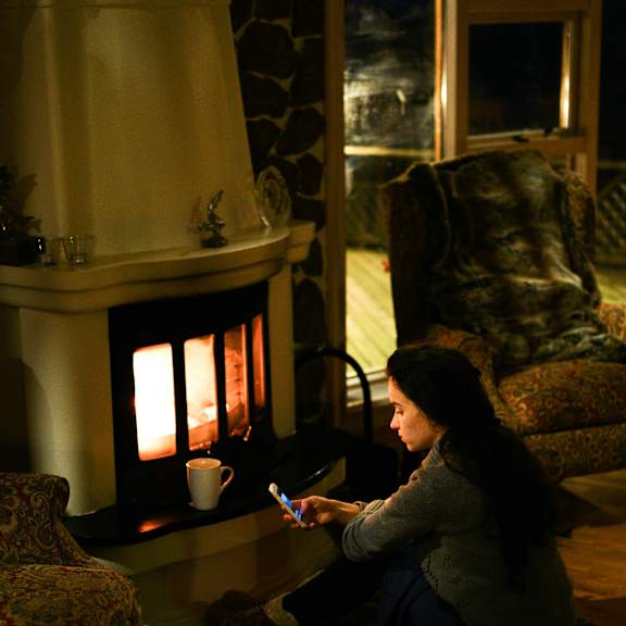 a woman sitting on the floor in front of a lit fireplace.