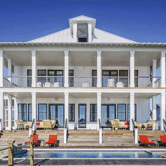 a white house with a pool in front.