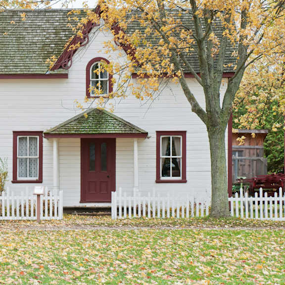a white house with a red door and a green roof.