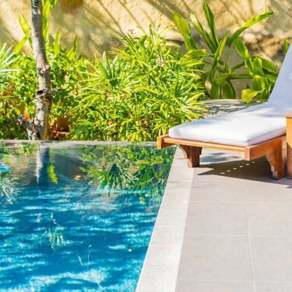 a poolside lounge chair with a white cushion and wooden frame at bluebell ridge, denver co 80202
