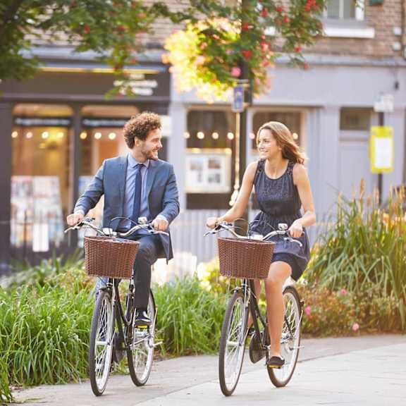 a man and a woman riding bicycles on a sidewalk.