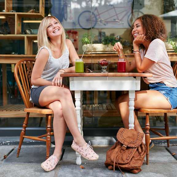 two women sitting at a table outside a cafe.