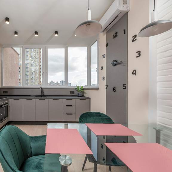 a modern kitchen with a green chair and a pink table.