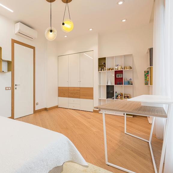 a bedroom with a bed, desk, and shelves.