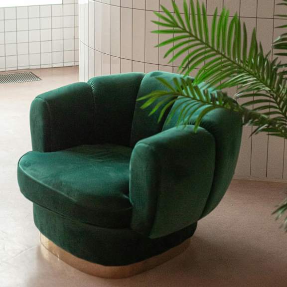 a green armchair with a wooden base is placed in a room.