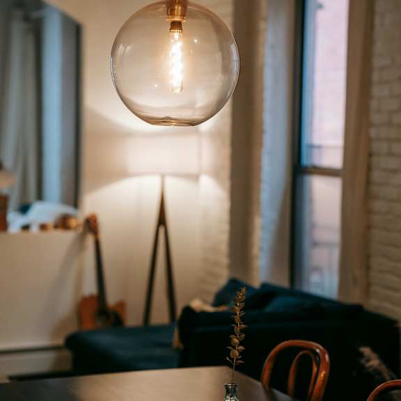 a table with a vase on it and a light bulb hanging from the ceiling.