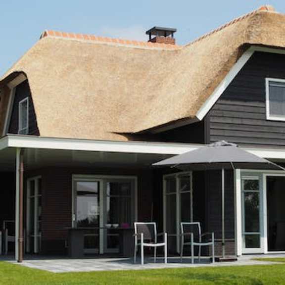 a house with a thatched roof and a covered patio.