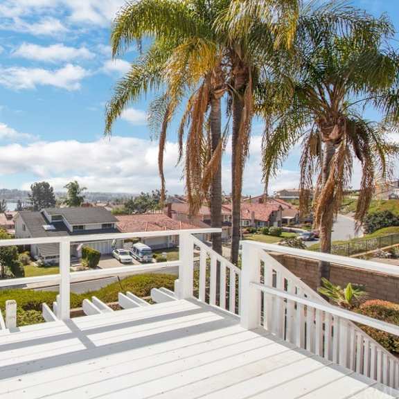 a white deck with a railing and palm trees in the background.