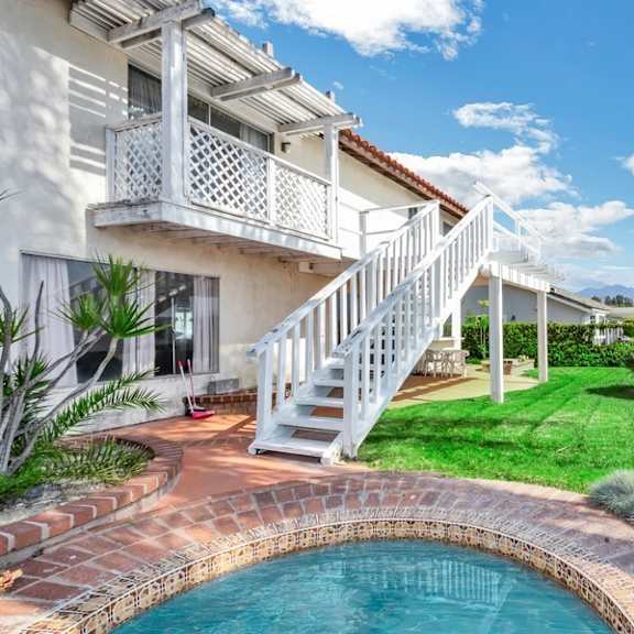 a white house with a pool in the backyard.
