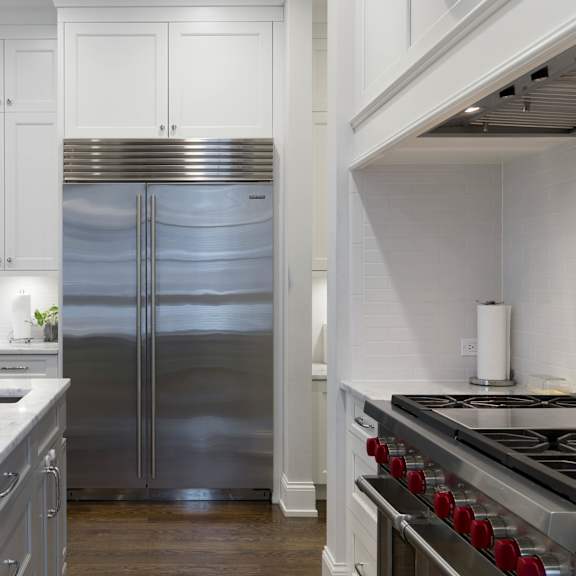 a modern kitchen with a stainless steel refrigerator and a marble countertop.