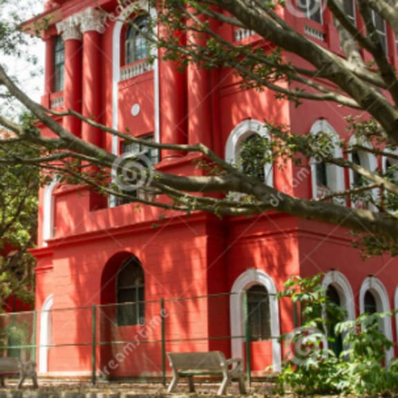 a red building with arched windows and a fence in front.