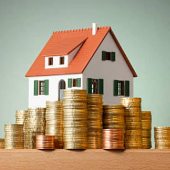 a small house is built on top of a pile of gold coins.