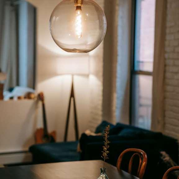 a table with a vase on it and a light bulb hanging from the ceiling.