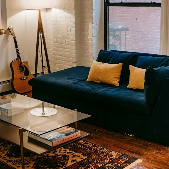 a living room with a blue couch and a guitar hanging on the wall.