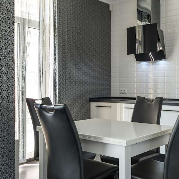 a white dining table with two black chairs in a modern kitchen.