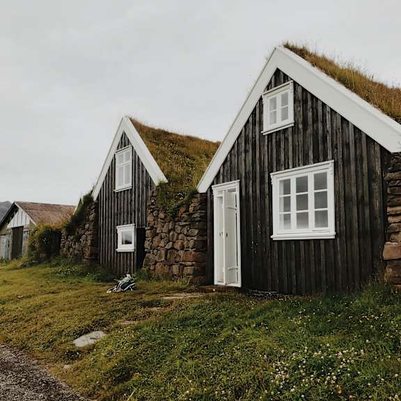 a small house with a grass roof sits in a field.