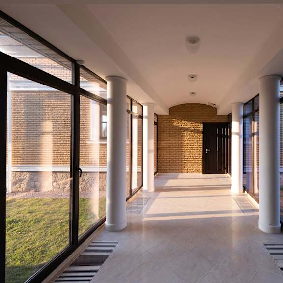 a long hallway with a brick wall and white columns.
