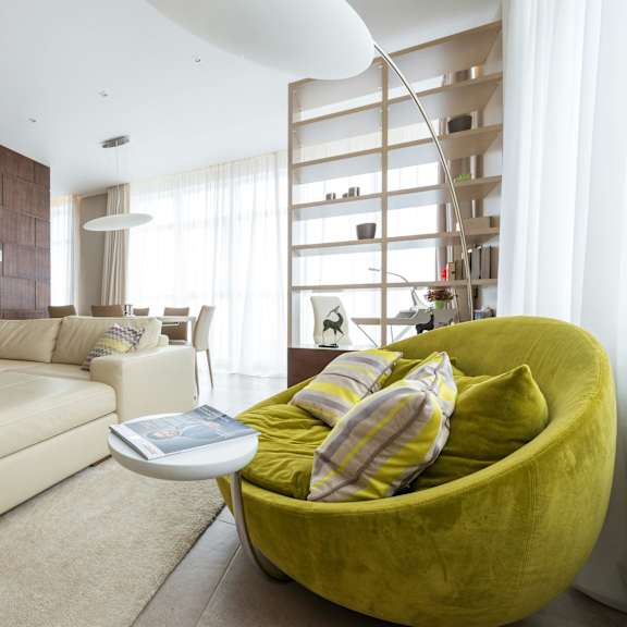 a modern living room with a green chair and a white couch.