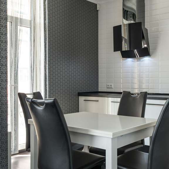 a white dining table with two black chairs in a modern kitchen.