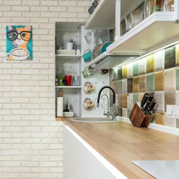 a kitchen with a white brick wall and a wooden counter.