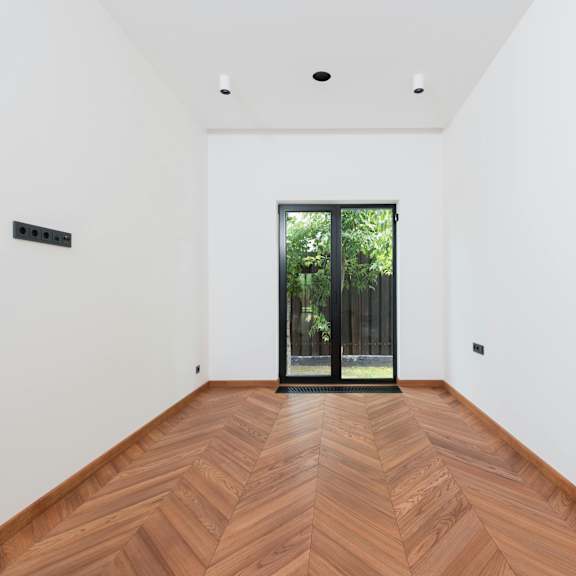 a room with a wooden floor and a glass door leading outside.