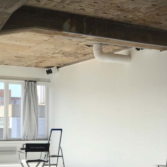 a chair with a laptop on it is in a room with a window.