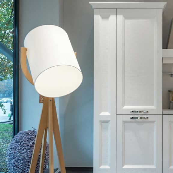 a white lamp stands next to a white cabinet in a kitchen.