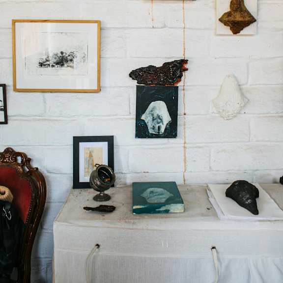 a white brick wall with a variety of objects including a globe, books, and framed pictures.