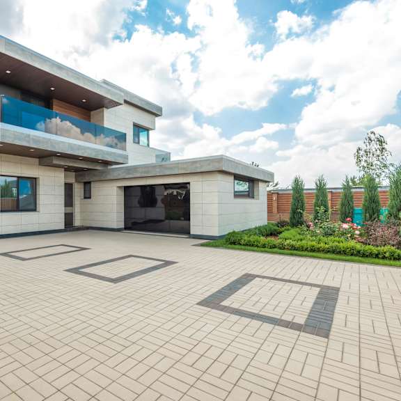 a modern house with a large driveway in front.