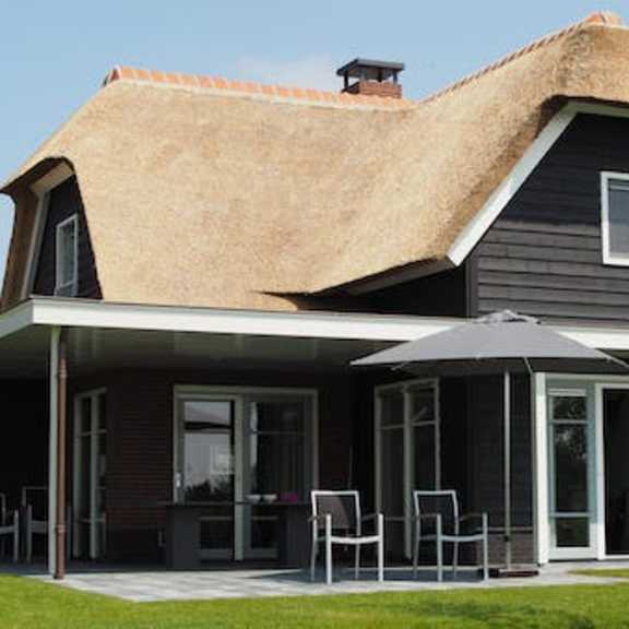 a house with a thatched roof and a covered patio.