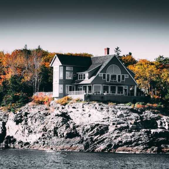 a house is built on a rocky outcrop by the water.