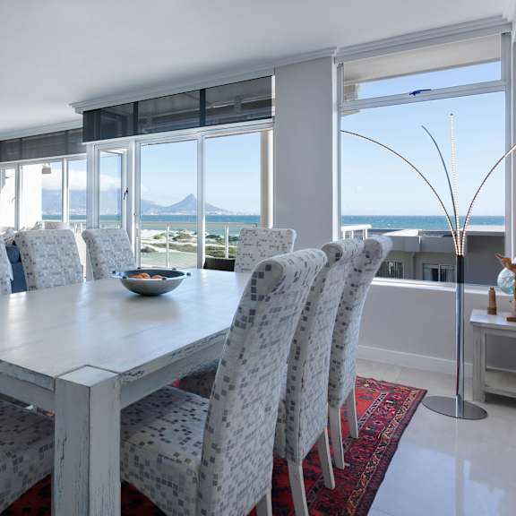 a dining room with a table and chairs with a view of the sea.