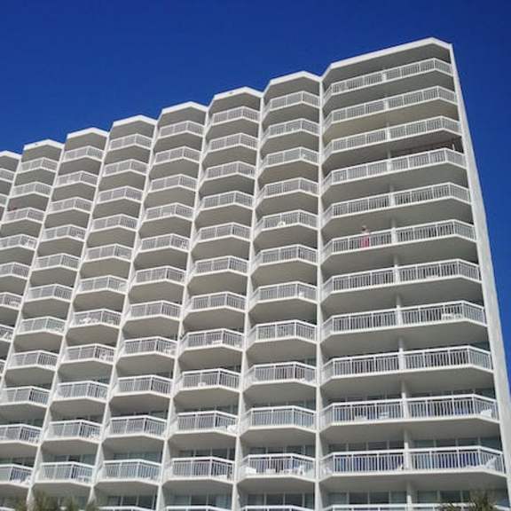 a tall white building with balconies on each floor.