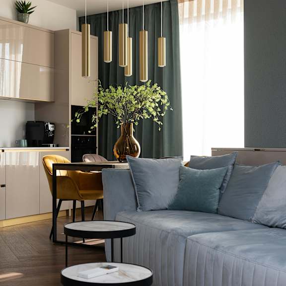a modern living room with a sofa, a coffee table, and a kitchen area in the background.