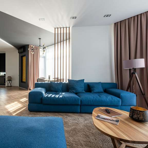 a modern living room with a blue sofa and a wooden coffee table.