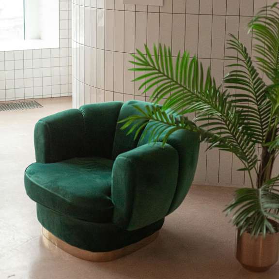 a green chair is in front of a tiled wall.