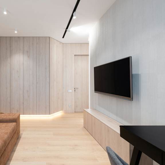 a modern living room with a brown couch and a flat screen tv mounted on the wall.
