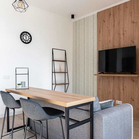 a modern dining area with a wooden table and grey chairs.