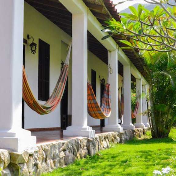 a porch with a bench and hammocks.