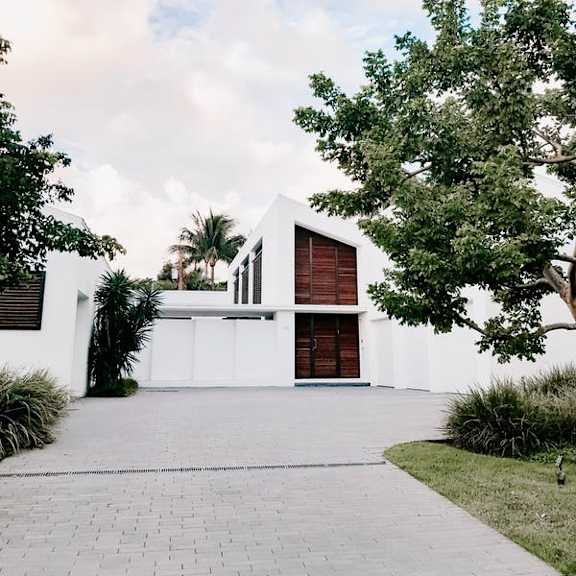 a white house with a red door and a tree in front.