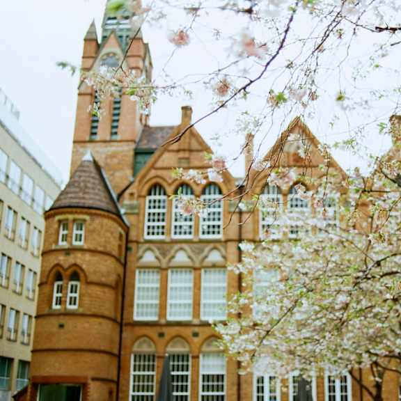 a large brick building with a clock tower in front of a tree