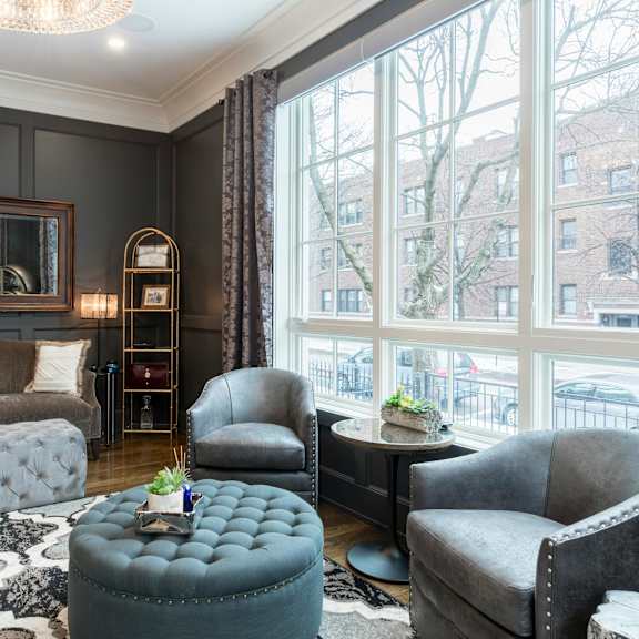 a living room with a grey couch, a grey armchair, a grey ottoman, and a black and white rug.