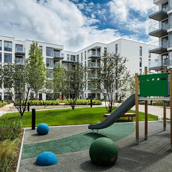 a playground with a green slide and blue and green balls. at cherrywood apartments, d18 vy3v
