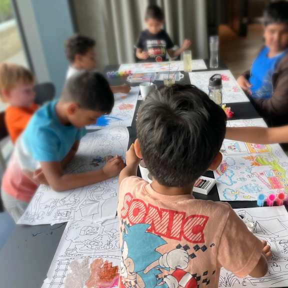 a group of children are sitting around a table drawing and coloring. at cherrywood apartments, d18 vy3v, dublin 18