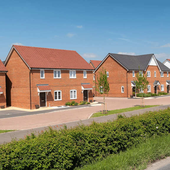 a row of red brick houses with green shrubbery in front.