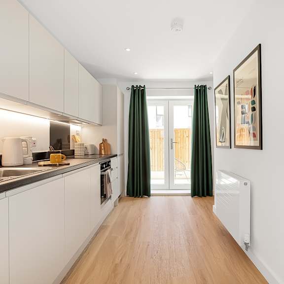 Thumbnail 3 of 11 A kitchen with white cabinets and a wooden floor.