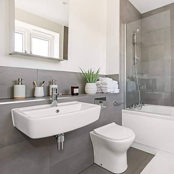 Thumbnail 4 of 6 A white toilet sits next to a sink in a modern bathroom.